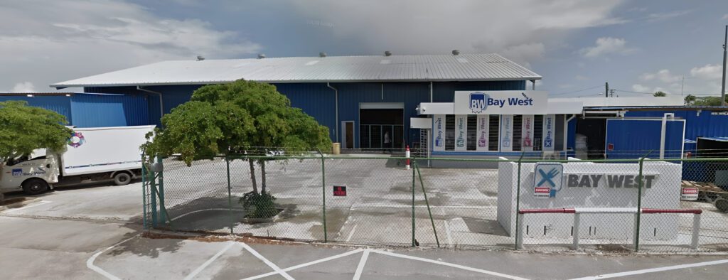 Bay West Caribbean headquarters building exterior with delivery trucks and signage