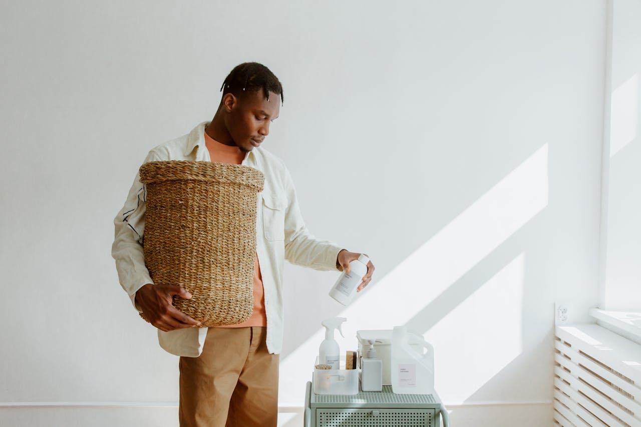 Man holding a laundry basket and selecting eco-friendly cleaning products.