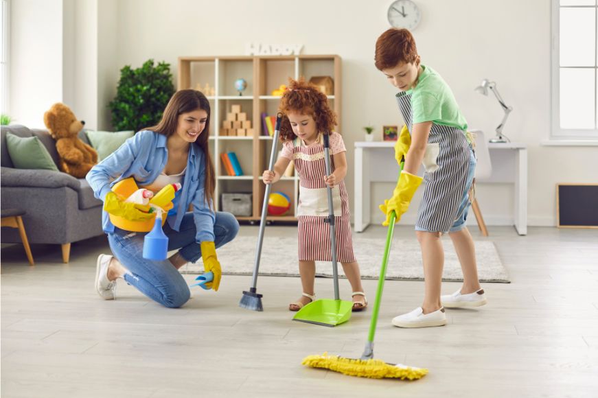 Family cleaning together using cleaning supplies and mops.